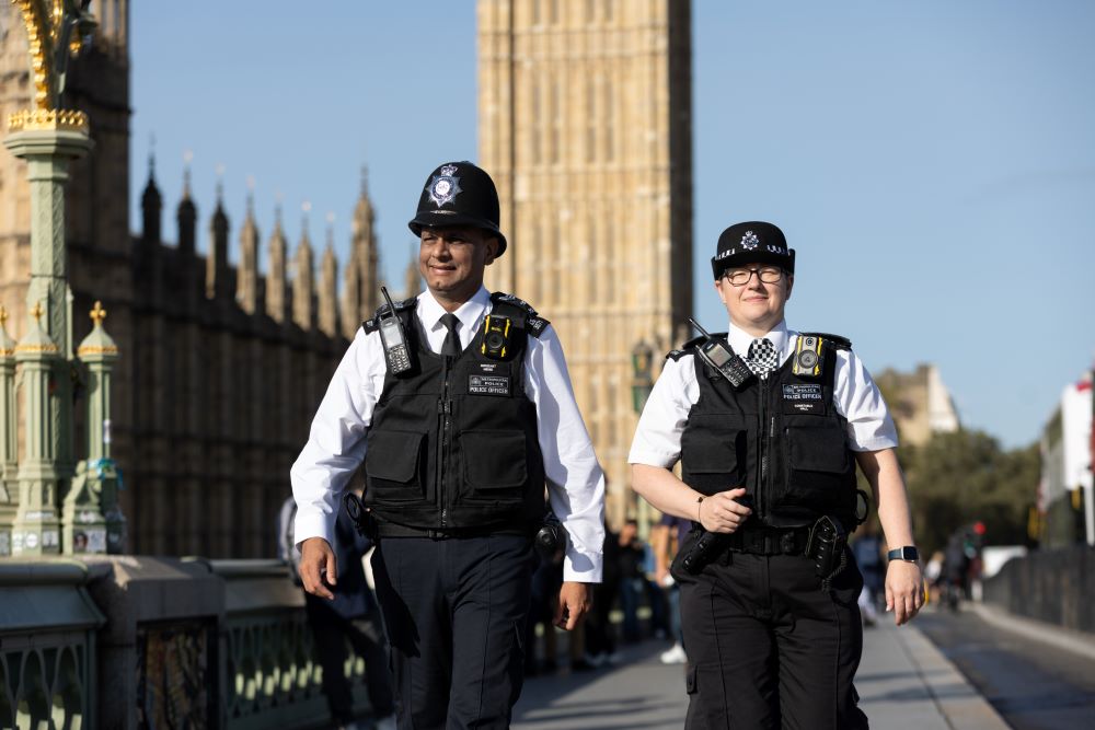 Two police male and female walking in street